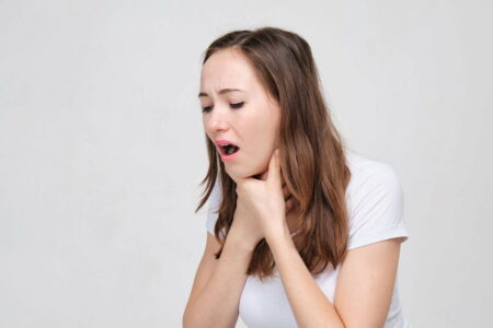 Woman in a white t-shirt clutching her throat due to breathing difficulties